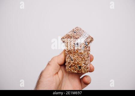 Homme main tenant des graines pour les oiseaux en forme de une maison sur fond blanc Banque D'Images