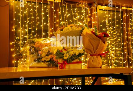 Des bouquets de fleurs se tiennent sur une table, sur fond de guirlande festive. Banque D'Images