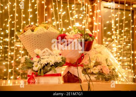 Des bouquets de fleurs se tiennent sur une table, sur fond de guirlande festive. Banque D'Images