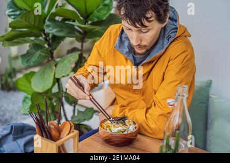 Homme mangeant le bol de poke biologique cru avec du riz et des légumes gros plan sur la table. Vue de dessus horizontale Banque D'Images