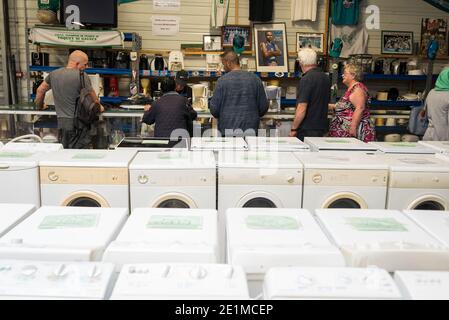 Site de la Communauté Lescar-Pau Emmaus (charité) (sud-ouest de la France). Machines à laver et personnes regardant les petits appareils électriques Banque D'Images