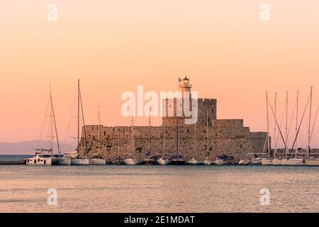 Coucher de soleil sur l'île grecque au-dessus de la forteresse Saint-Nicolas, port de Mandraki, ville de Rhodes, île de Rhodes, Grèce Banque D'Images