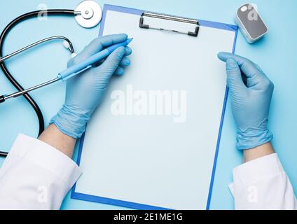 mains du médecin dans des gants médicaux bleus tient un oxymètre de pouls électronique sur un fond bleu , vue de dessus Banque D'Images