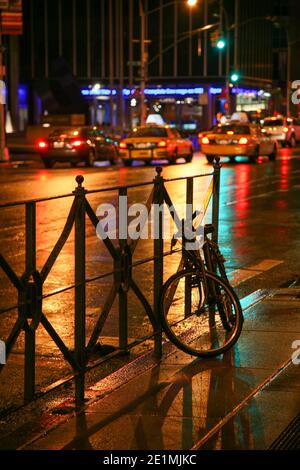 New York nuit scène de rue avec vélo menant aux taxis jaunes dans le loin. NY, ÉTATS-UNIS Banque D'Images