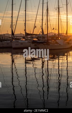 Des bateaux à voile amarrés au coucher du soleil dans les eaux du port de l'île Saronique d'Aegina ( Egina ) près d'Athènes, Golfe Saronique, Grèce Banque D'Images