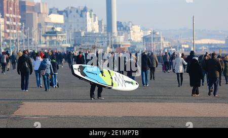 Hove, East Sussex, Royaume-Uni. 08 janvier 2021. Météo au Royaume-Uni : une journée froide mais lumineuse et ensoleillée sur la promenade et la plage en bord de mer comme la foule de gens, certains portant des masques de visage profitent du beau temps. Une paddle-boarder part en mer. Crédit photo : Paul Lawrenson/Alay Live News Banque D'Images