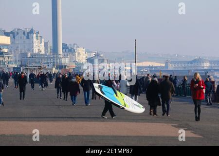 Hove, East Sussex, Royaume-Uni. 08 janvier 2021. Météo au Royaume-Uni : une journée froide mais lumineuse et ensoleillée sur la promenade et la plage en bord de mer comme la foule de gens, certains portant des masques de visage profitent du beau temps. Une paddle-boarder part en mer. Crédit photo : Paul Lawrenson/Alay Live News Banque D'Images