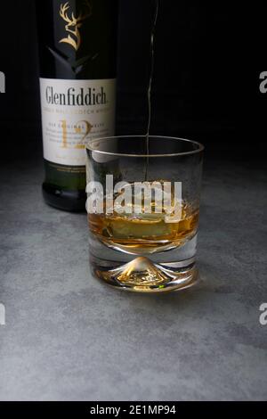 Whisky single malt Glenfiddich 12 ans dans un verre avec glace sur un plan de travail en marbre. Banque D'Images