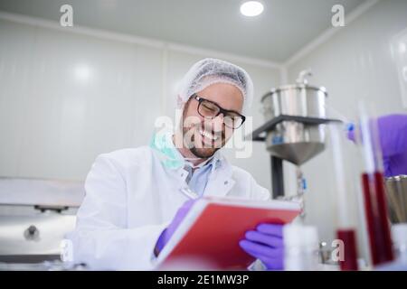 Un homme frayant écrit les résultats des tests lorsqu'il est assis dans le laboratoire. Banque D'Images