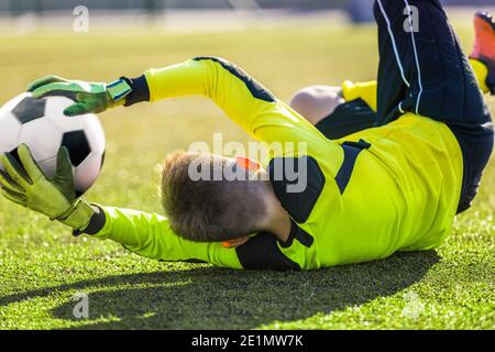 Football Goalie attraper ballon. Objectif de sauvegarde de gardien de but pour jeune garçon. Ballon de gardien de but acrobatique Save. Joueur de football dans un but lors d'une Sunny Summer Day. SOC Banque D'Images