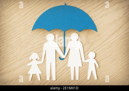 Silhouette de famille en papier avec parapluie sur fond en bois - concept de la protection de la famille Banque D'Images