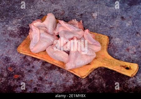 Ailes de poulet fraîches et crues sur le panneau de bois de la cuisine avec des ingrédients et épices Banque D'Images