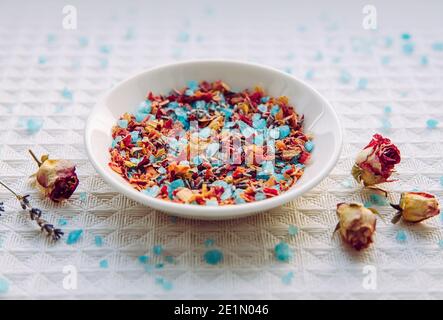 Mélange de sel de bain aux pétales de rose maison pour l'aromathérapie et la détente dans la baignoire et le bain. Assiette avec mélange de sel de bain de couleur bleue. Banque D'Images