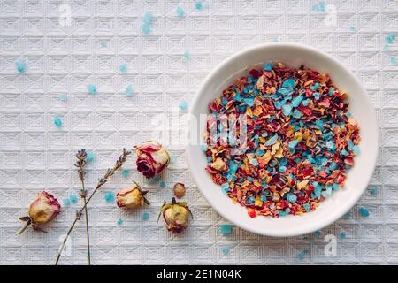 Mélange de sel de bain aux pétales de rose maison pour l'aromathérapie et la détente dans la baignoire et le bain. Assiette avec mélange de sel de bain de couleur bleue. Banque D'Images