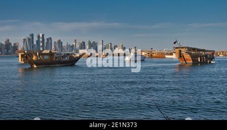 Vue de Doha depuis la promenade de la corniche, après-midi, prise de vue montrant des huws Avec le drapeau du Qatar dans le golfe arabe en premier plan et les nuages dans le ciel en arrière-plan Banque D'Images