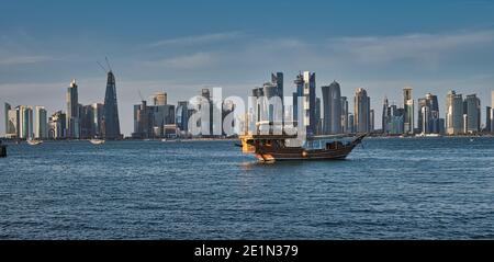 Vue de Doha depuis la promenade de la corniche, après-midi, prise de vue montrant des huws Avec le drapeau du Qatar dans le golfe arabe en premier plan et les nuages dans le ciel en arrière-plan Banque D'Images