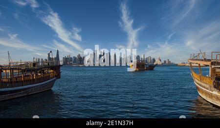 Vue de Doha depuis la promenade de la corniche, après-midi, prise de vue montrant des huws Avec le drapeau du Qatar dans le golfe arabe en premier plan et les nuages dans le ciel en arrière-plan Banque D'Images