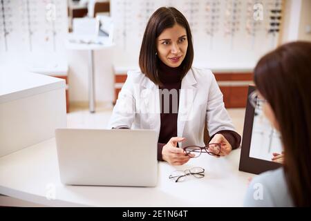 Ophtalmologiste offrant différentes lunettes à un visiteur Banque D'Images