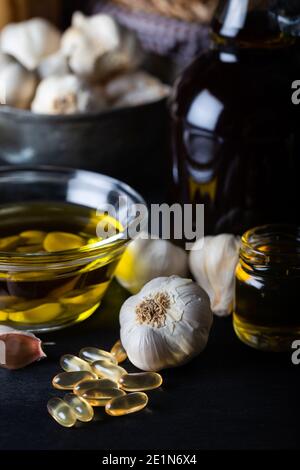 Huile d'ail et d'ail mûrs et crus dans un verre de bouteille sur fond de bois foncé. Garlics et huile d'olive. Banque D'Images