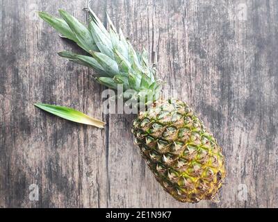 Un ananas entier posé sur une table en bois Banque D'Images