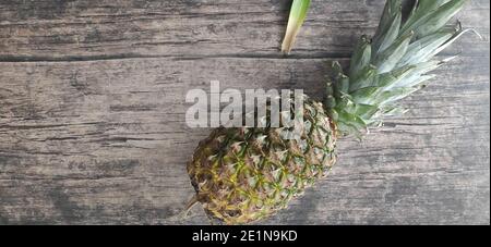 Un ananas entier posé sur une table en bois Banque D'Images