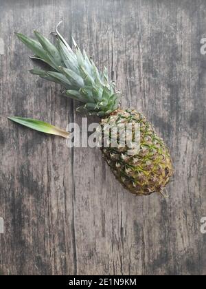 Un ananas entier posé sur une table en bois Banque D'Images