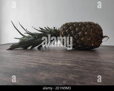 Un ananas entier posé sur une table en bois Banque D'Images