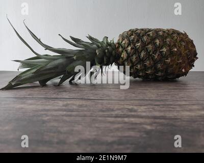 Un ananas entier posé sur une table en bois Banque D'Images