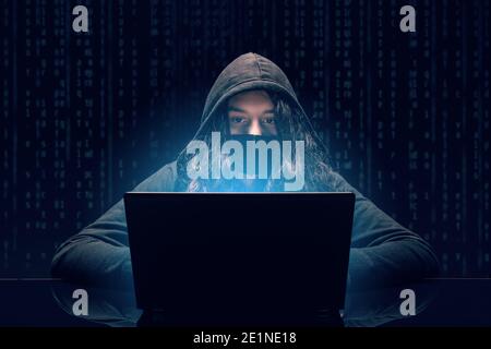 Le piratage et les programmes malveillants. Pirate utilisant un ordinateur portable avec interface numérique de code binaire. Banque D'Images
