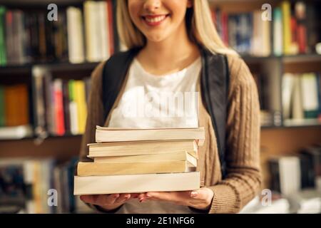 Gros plan d'une femme étudiant mains pleines de livres. Banque D'Images