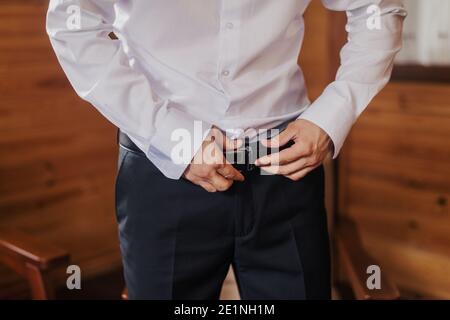 Gros plan sur les mains de l'homme portant la ceinture sur le pantalon. Banque D'Images