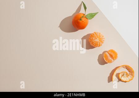 Arrière-plan créatif avec des mandarines fraîches ou orange sur fond beige pastel. Peu de fruits d'été à plat. Banque D'Images