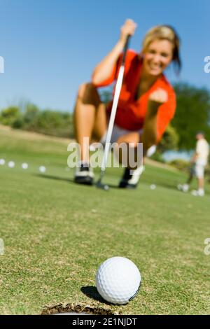 Photo de la femelle Golfer observant Putt Sink Banque D'Images