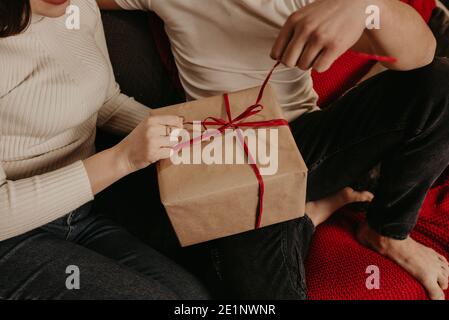 Homme et femme couple dans l'amour ouvrir des boîtes-cadeaux dénoue un noeud près de l'arbre de noël. Maison décorée pour le nouvel an. Le matin de Noël. Intérieur de l'appartement. Banque D'Images