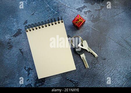 ensemble de clés, bloc-notes et petit cadeau sur fond gris. Banque D'Images