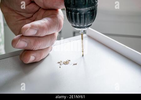 la collecte de meubles, une personne fore un trou avec une perceuse électrique. Travaillez comme un collecteur de meubles dans la maison. Mise au point sélective. Banque D'Images