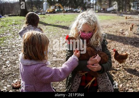 fille aux cheveux blonds tenant le poulet sur une ferme Banque D'Images