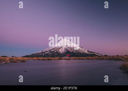Jeune femme sur une pose de yoga au pied du Mont Taranaki au début de l'heure bleue, Nouvelle-Zélande Banque D'Images