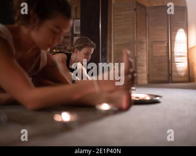 Les jeunes amies qui font Pascimottanasana posent près de l'encens aromatique dans studio Banque D'Images