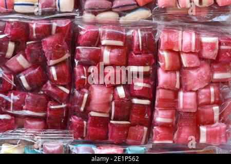 Bonbons multicolores dans un emballage en plastique transparent comme arrière-plan. Banque D'Images