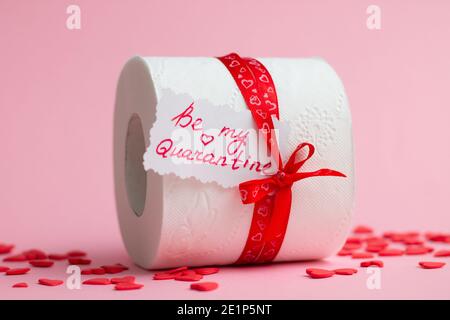 Rouleau de papier toilette en cadeau de la Saint-Valentin avec note « soyez ma quarantaine », à côté de coeurs rouges sur fond rose Banque D'Images