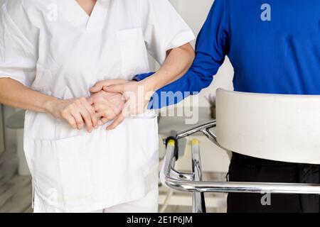 infirmière soignante féminine, tenant la main du patient, soutenant le patient handicapé assis sur un fauteuil roulant à l'hôpital, jeune médecin soignant aide patient paralysé. Photo de haute qualité Banque D'Images