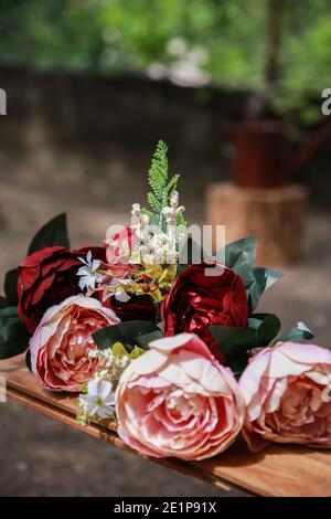 Bouquet de mariage de roses beiges et rouges à l'extérieur sur la balançoire décorée. Bouquet de fleurs d'été sur une balançoire à l'extérieur Banque D'Images