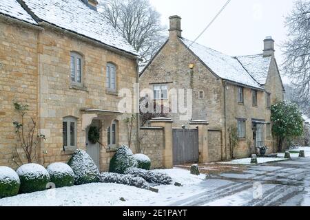 Cotswold cottage en pierre avec couronne de noël dans la neige de décembre. Taynton, Cotswolds, Oxfordshire, Angleterre Banque D'Images