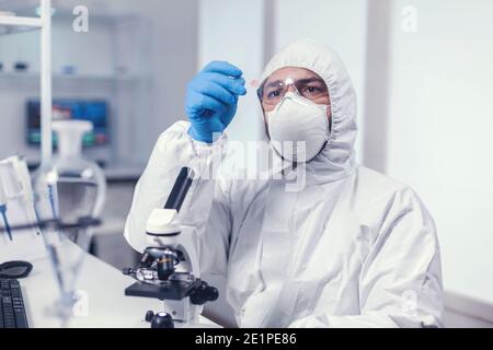 Scientifique médical tenant une lame de verre de microscope vêtue d'epi pendant la covid19. Examen de l'évolution des vaccins à l'aide de la haute technologie pour la recherche d'un traitement contre le virus covid19. Banque D'Images