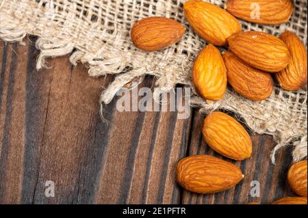 Les amandes sont dispersées sur une table en bois recouverte d'un tissu homesjeu avec une texture rugueuse Banque D'Images