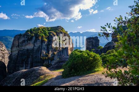Vue en soirée sur le paysage typique de Meteora, Grèce. Roches sédimentaires massives, falaises, montagnes, vallée. Ciel bleu et grands nuages. Mise au point sélective. Banque D'Images