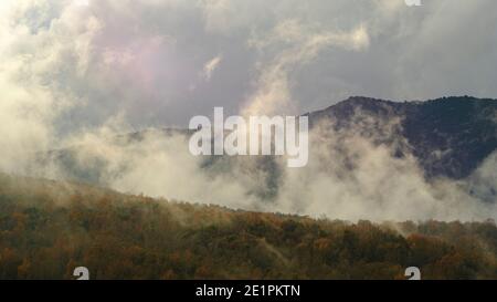 Les nuages grandissent sur un pic de montagne de forêt froide dans un paysage d'hiver Banque D'Images