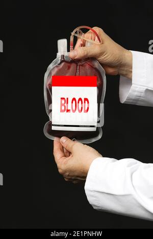Un médecin en manteau blanc tenant un sac de transfusion sanguine. Isolé sur fond sombre Banque D'Images