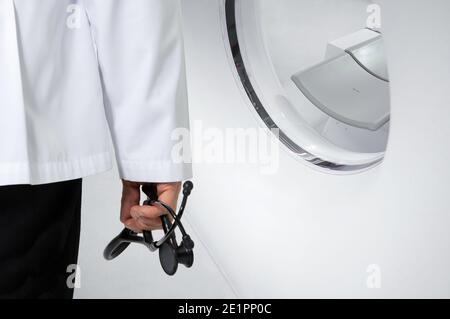 Médecin tenant un stéthoscope noir devant un scanner CT. Banque D'Images
